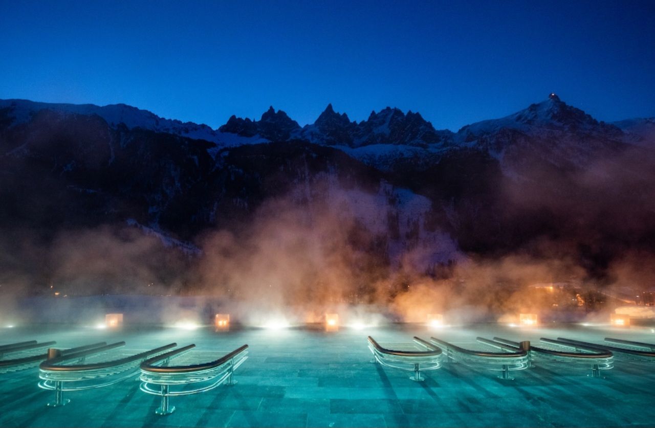 Une zone de sources chaudes où s'échappent des volutes de vapeur, entourée de montagnes.