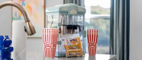 Ein Popcornmacher auf einer Küchenarbeitsplatte mit roten und weißen Streifen-Popcorndosen und einer Tüte Popcorn.