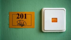 A yellow sign with the number 201 and a white light switch on a green wall. - Espace Chaleureux , Wifi + Netflix Free, Sécurisé (Douala)