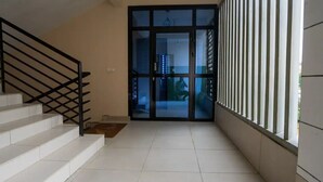 A staircase leading to a glass door entrance, a tiled floor, and a white railing. - Espace Chaleureux , Wifi + Netflix Free, Sécurisé (Douala)