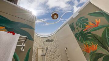 A bathroom with a shower, a towel rack, and a wall mural of tropical leaves and flowers.