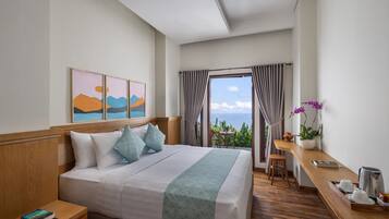 A hotel room with a large bed, a desk, and a view of the ocean.