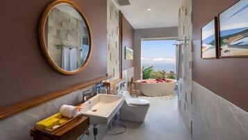 A modern bathroom with a large mirror, a sink, a toilet, and a bathtub.