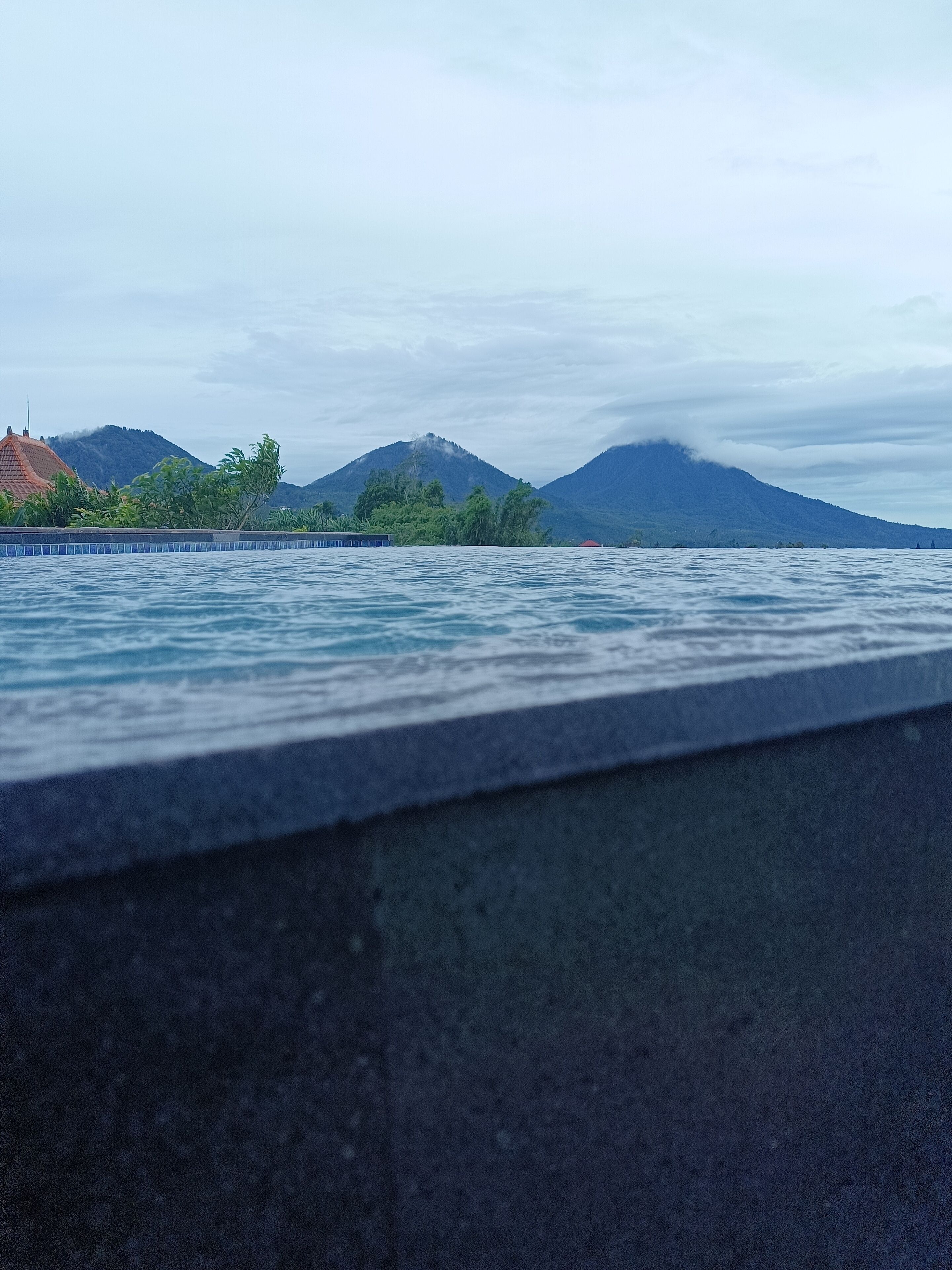Vista de un cuerpo de agua con montañas al fondo y un borde de hormigón en primer plano.