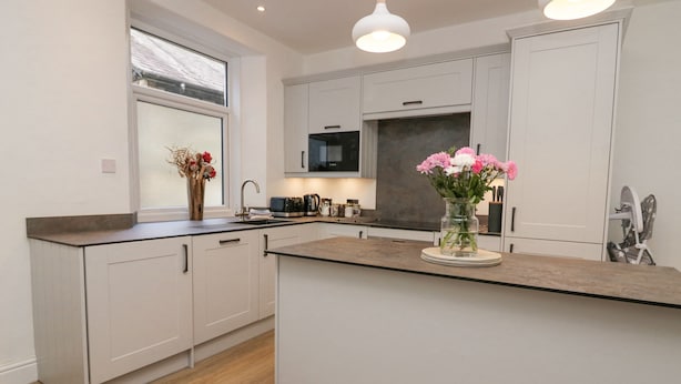 A modern kitchen with white cabinets, a central island, and a window with a view.