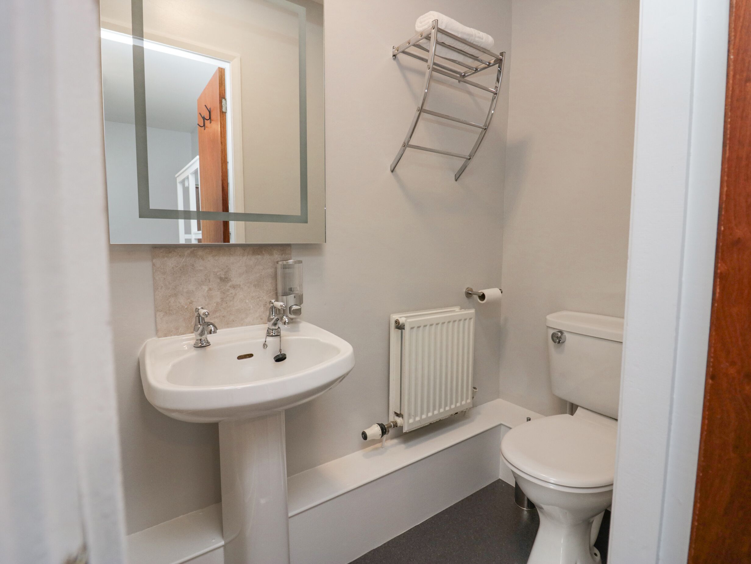 A bathroom with a white sink, a toilet, a towel rack, and a mirror.