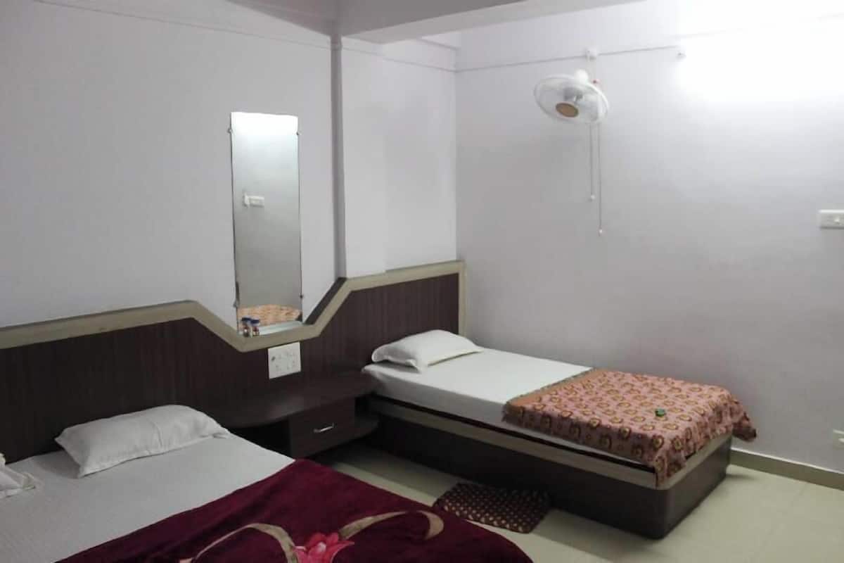 A bedroom with two beds, a mirror, a bedside table, and a ceiling fan.