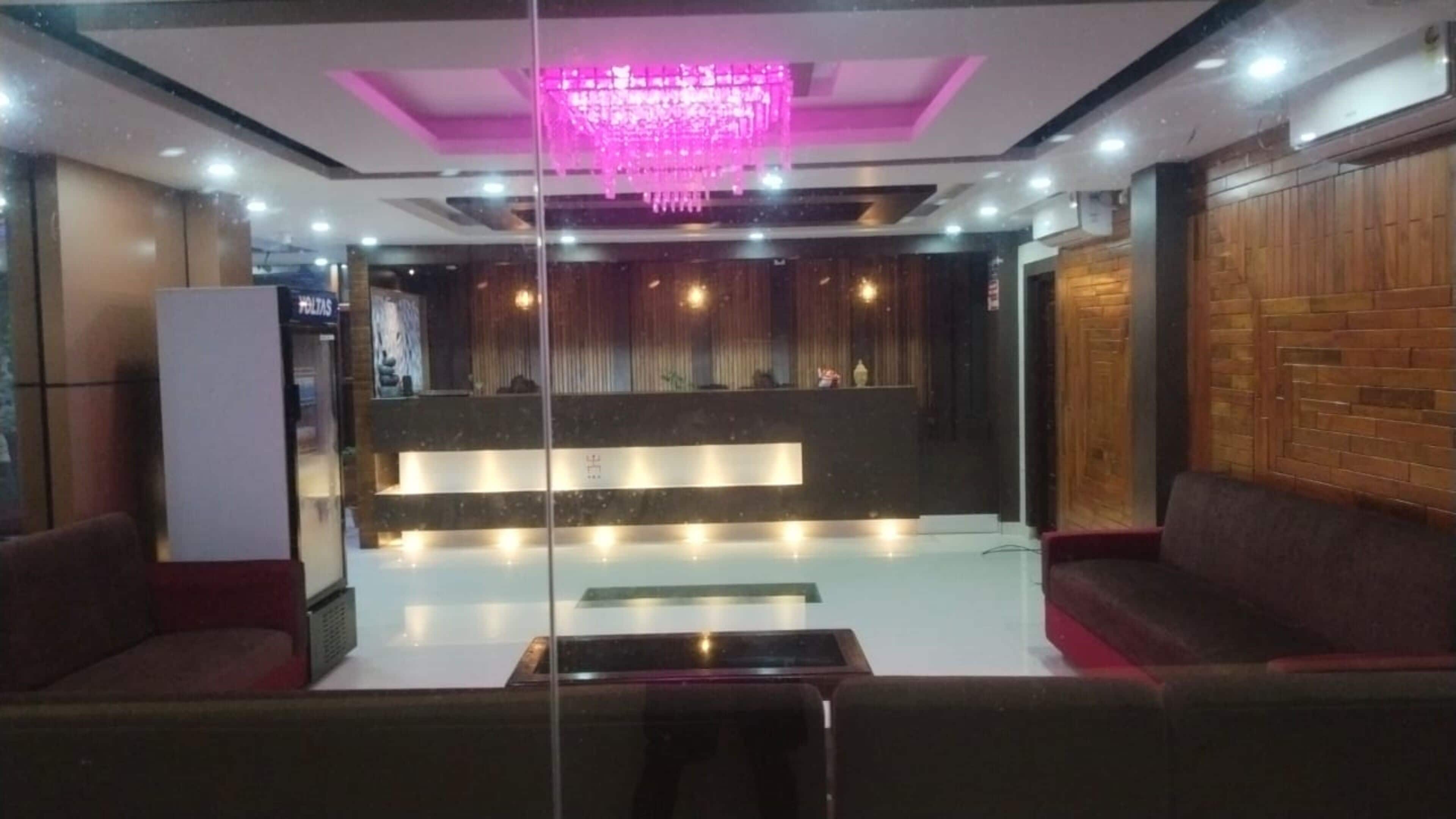 A modern lobby with a reception desk, seating area, and a decorative chandelier.