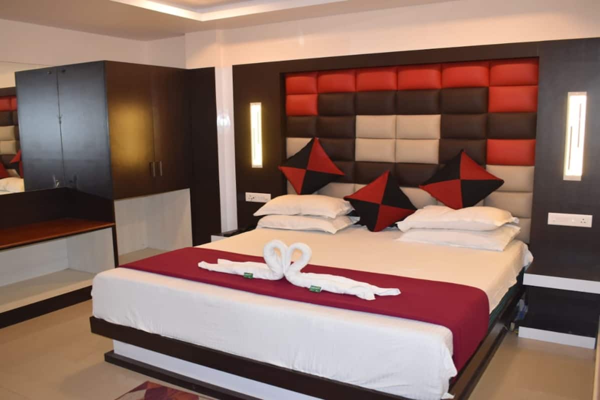 A modern hotel room with a large bed, a built-in wardrobe, and a mirror.