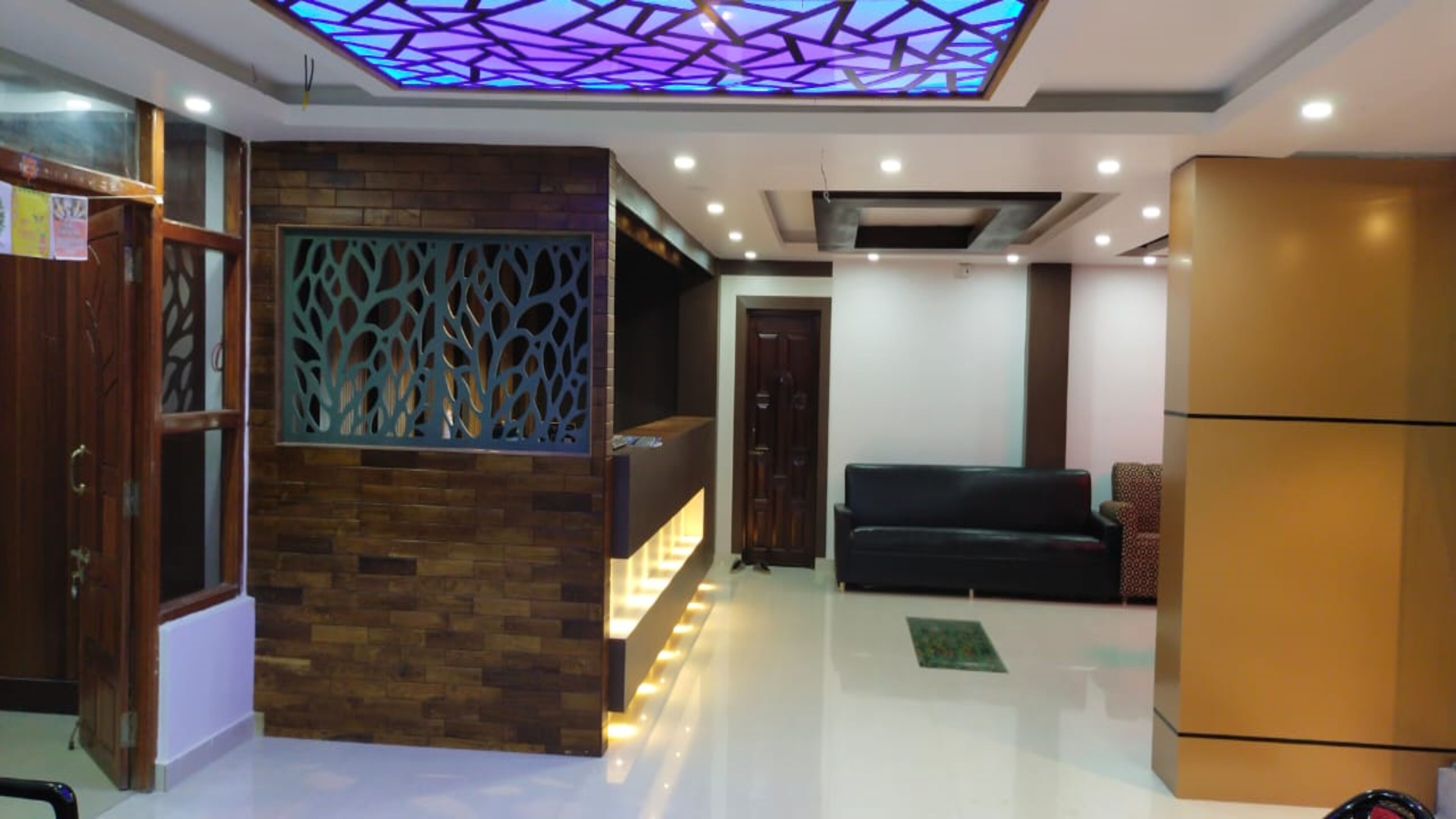 A modern interior with a reception desk, a patterned wall, a sofa, and a refrigerator.