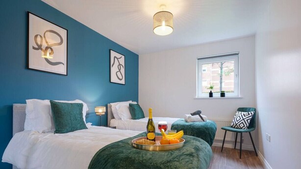 Ein Hotelzimmer mit zwei Betten, einem Esstisch mit Frühstück, einem Fenster und Bildern an der Wand.