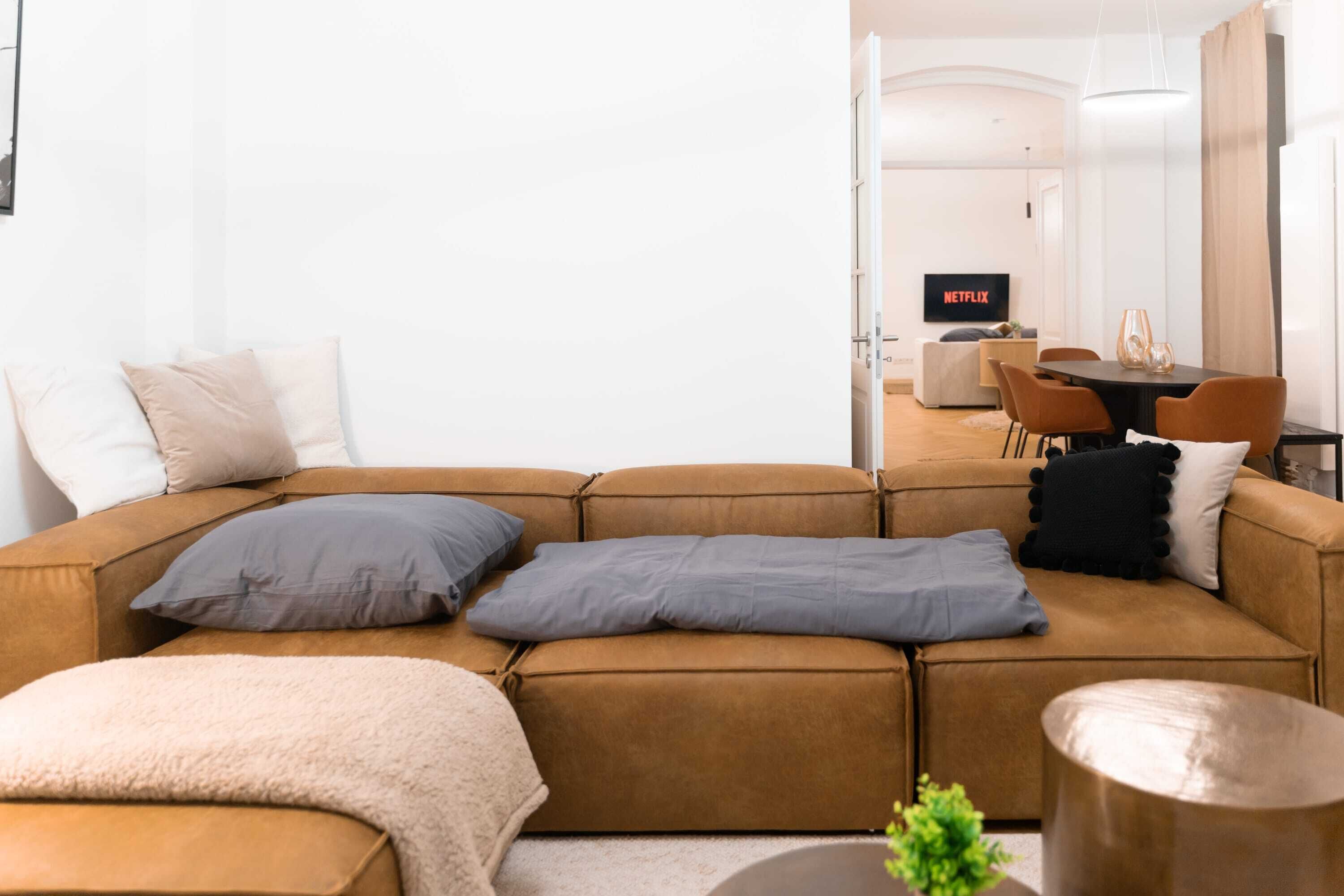 En moderne stue med en brun hjørnesofa, et sofabord og et spiseområde med bord og stole.