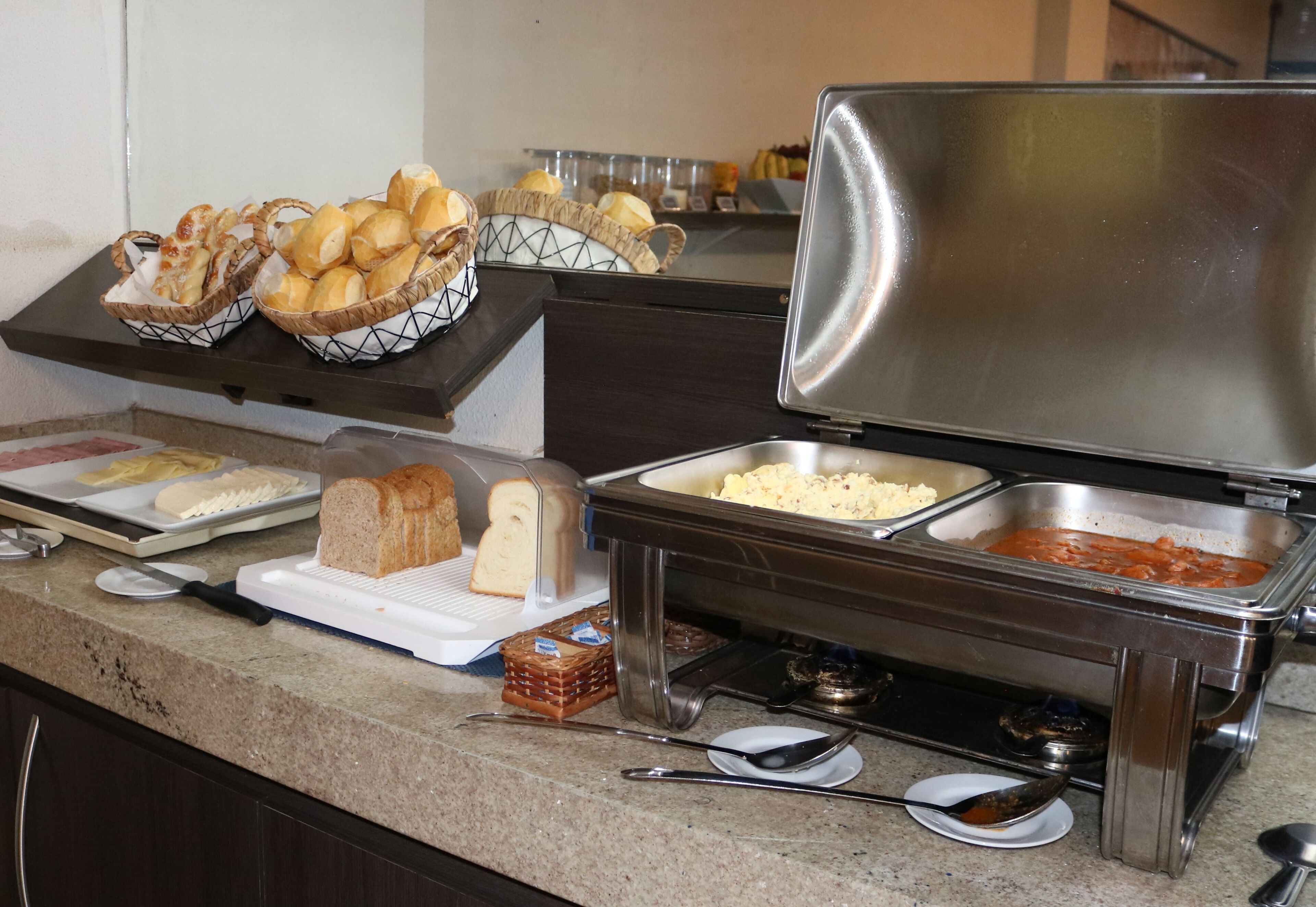 Ein reichhaltiges Buffet mit Brot, Käse und einem Gericht auf Tomatenbasis.
