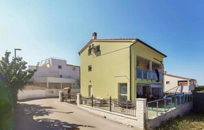 A two-story building with a balcony, a fenced area, and a clear sky. - Beach front home in Medulin with WiFi (Medulin)