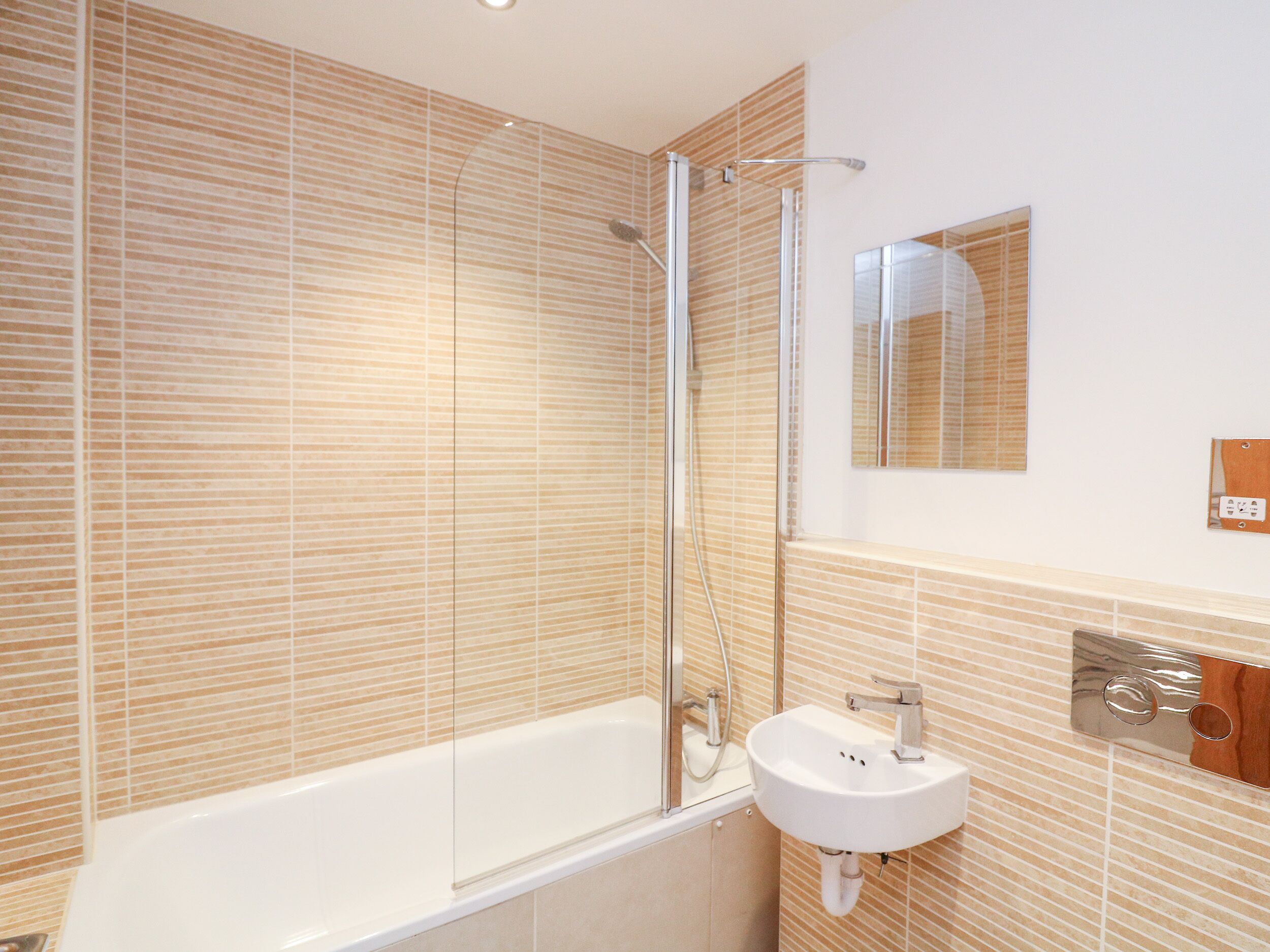 Een moderne badkamer met een douchecabine van glas, een wit bad en een wastafel met een spiegel erboven.