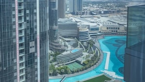 A high-rise building with a modern architectural design, featuring a curved structure and a pool area with a blue pool.