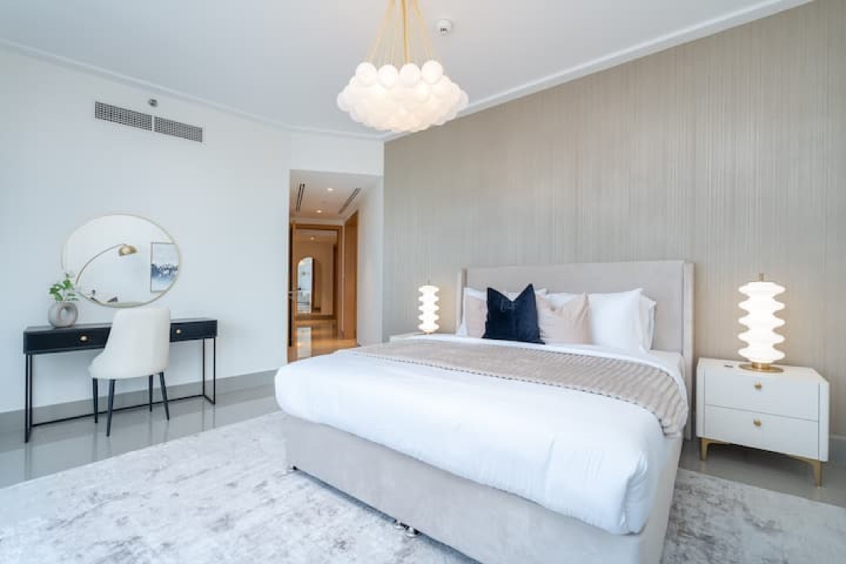 A modern bedroom with a large bed, a desk, and a chair.