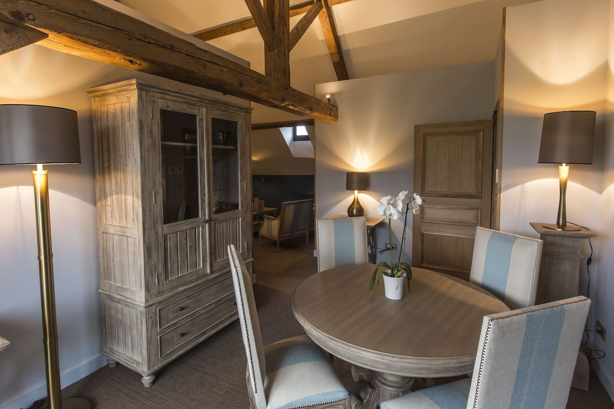 A dining area with a round table, upholstered chairs, and a cabinet.