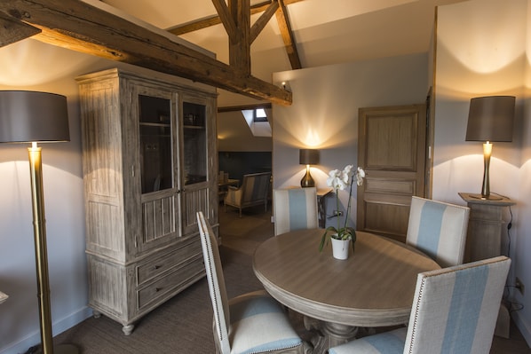 A dining area with a round table, upholstered chairs, and a cabinet. - Domaine de Rymska & Spa - Relais & Châteaux (Saint-Jean-de-Trézy)