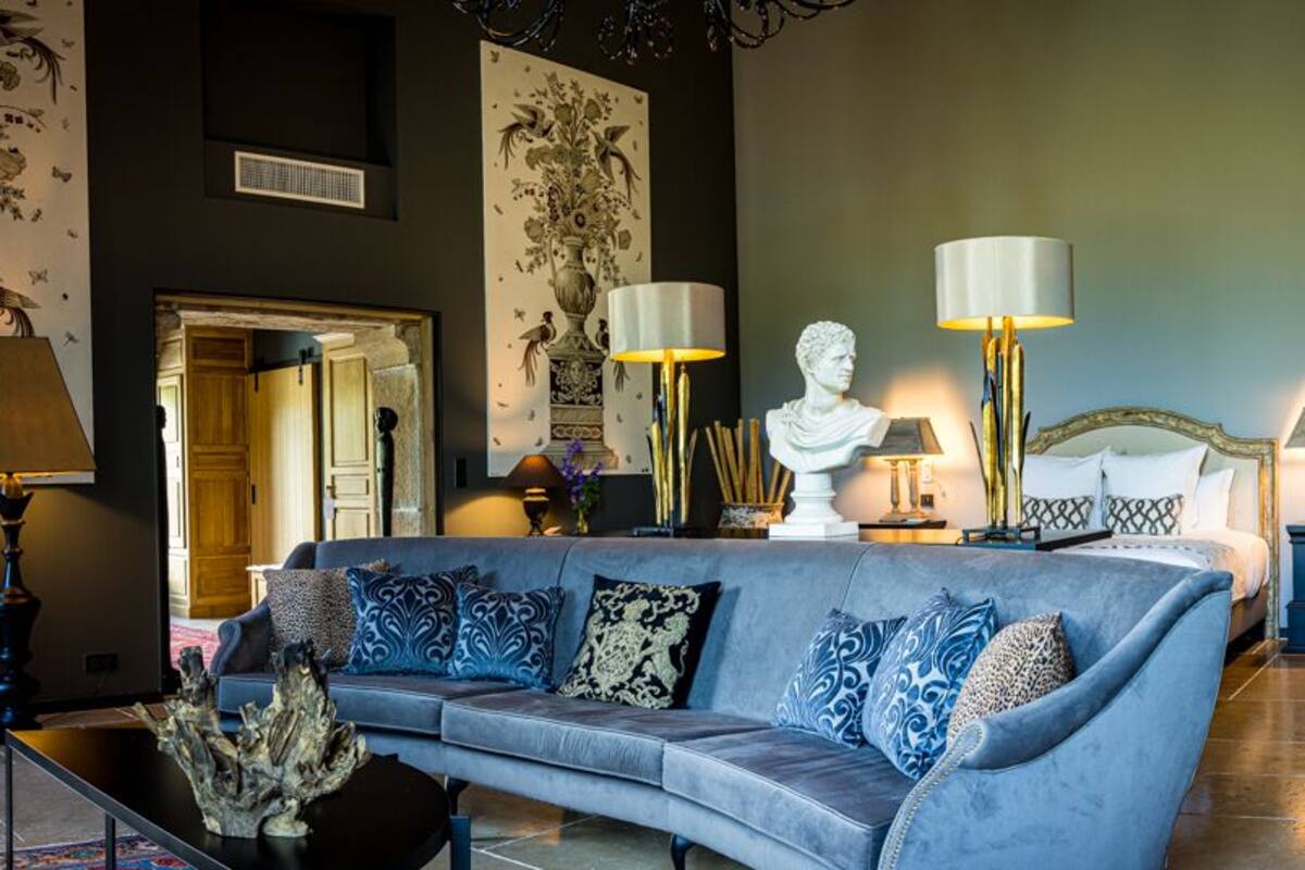A modern living room with a blue sofa, decorative lamps, and a bust sculpture.