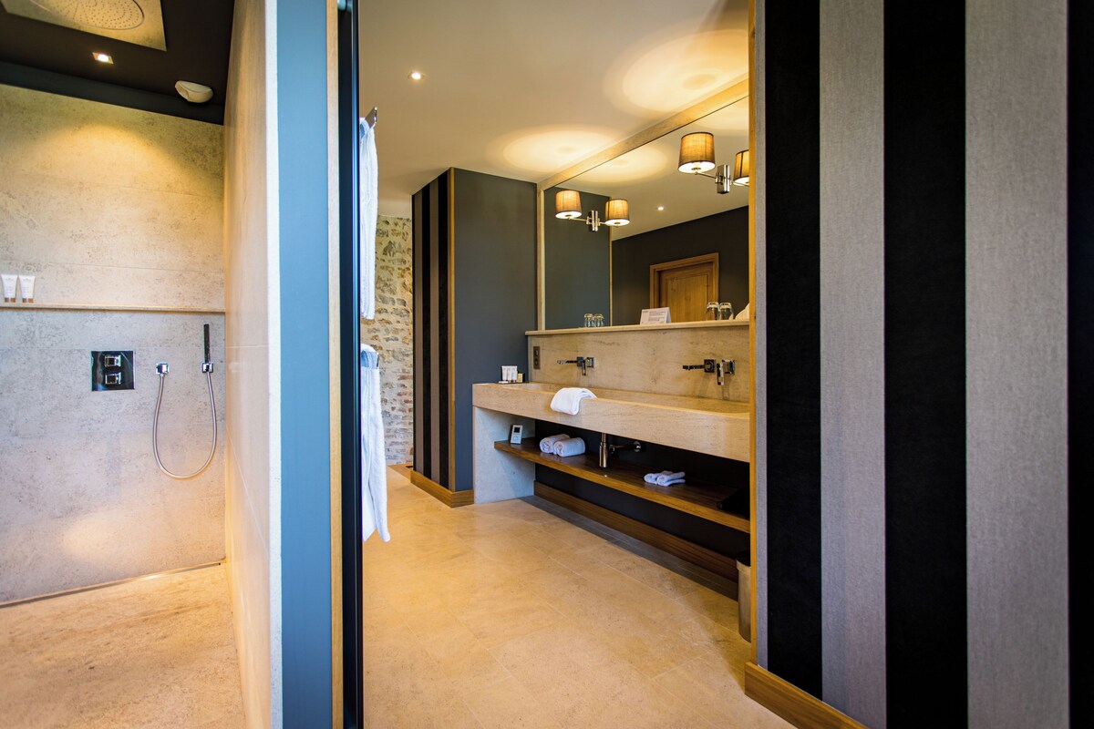 Un baño moderno con ducha, un espejo grande y un tocador con toallero.