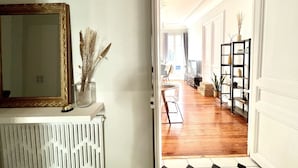 A hallway with a white radiator, a mirror with a gold frame, and a vase with dried flowers.