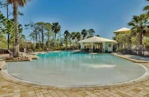 A large outdoor swimming pool with a covered pavilion, surrounded by palm trees and a clear sky. - Salty Days - 5BR/3BA NatureWalk Home - Sleeps 12 - Golf Cart & Community Pools (Santa Rosa Beach)