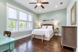 Une chambre à coucher comprenant un lit, un ventilateur de plafond, une table de chevet, un banc et une commode.