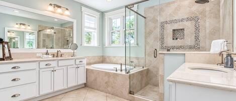 A modern bathroom with a walk-in shower, a freestanding bathtub, and a vanity with a large mirror.