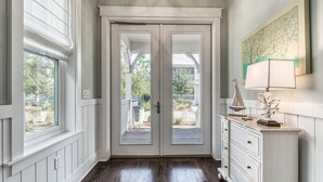 A hallway with a double door leading to an outdoor area, a white dresser with a lamp, and a framed artwork on the wall. - Seagrove Beach Paradise: Salty Days - Your Dream 30A Getaway! (Santa Rosa Beach)