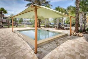 A swimming pool with a shaded area and palm trees in the background. - Salty Days - 5BR/3BA NatureWalk Home - Sleeps 12 - Golf Cart & Community Pools (Santa Rosa Beach)