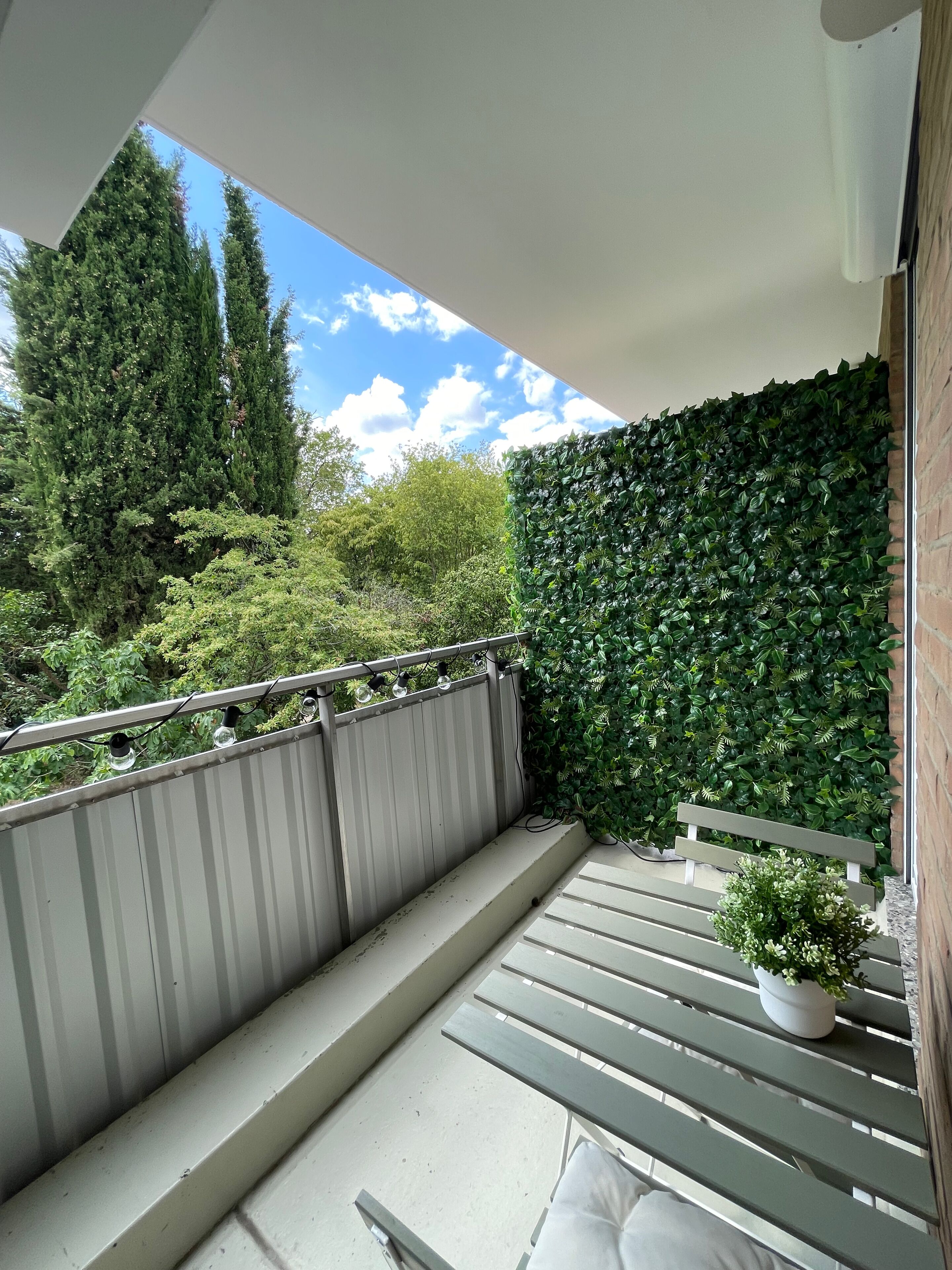 Ein Balkon mit Holzgeländer, einer Bank und einem Blumentopf.
