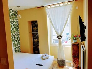 A hotel room with a bed, a remote control, a potted plant, and a television on the wall. - Vichy Sejour (Vichy)