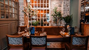 A cozy restaurant with a stone wall, wooden furniture, and a large window with a view. - The Ashford Arms (Bakewell)