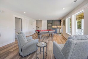 Relax in this stylish living room with a pool table, comfortable seating, and a fully equipped kitchen area.