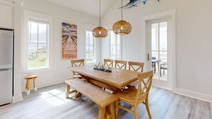 A spacious dining area with a wooden table and benches, large windows, and a ceiling-mounted fish sculpture.