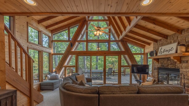 A spacious living room with a large sectional sofa, wooden beams, and a stone fireplace. - Turrach Ridge Retreat by Innsbrook Vacations! (Innsbrook)