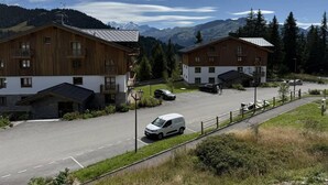 A hotel with two wooden buildings, a parking area, and a mountain backdrop.