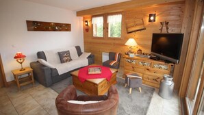 A cozy living room with a sofa, a coffee table, a TV, and a fireplace.