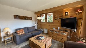 A cozy living room with a sofa, a coffee table, a TV, and a wooden cabinet.