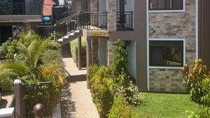 A two-story house with a tiled roof, a paved pathway, and lush greenery. - BAVAH AIRPORT HOTEL (Entebbe)