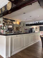 A reception area with a counter labeled "RECEPTION," a coffee machine, and a chalkboard menu.
