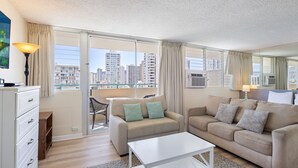 Una sala de estar moderna con un sofá, una mesa de centro y vistas de la ciudad a través de amplias ventanas.