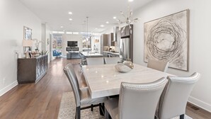 A modern dining area with a marble table, leather chairs, and a large abstract painting on the wall. - Always A Guest Favorite! Luxe 3 Level Home+ HUGE Rooftop Deck w/TV, fireplace! (Berry Hill)