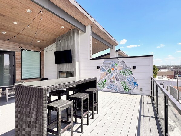Een terras buiten met een bar, zitplaatsen en een kaartmuur.