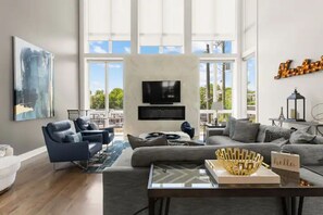 Een moderne woonkamer met een groot raam, een flatscreen televisie en een bank.