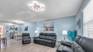 A living room with a sofa, armchairs, a coffee table, and a dining area with a table and chairs. - Walk 2 Beach ~ Pools ~ Gulf Highlands 108 (Panama City Beach)