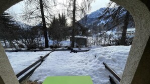 Vihreä pöytä ja tuolit lumisessa ulkotilassa, jossa on myös penkkejä ja kivirakenteita.