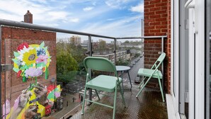A balcony with a view of a cityscape, featuring a mural of flowers and a brick wall. - City Gate Guest House (London)
