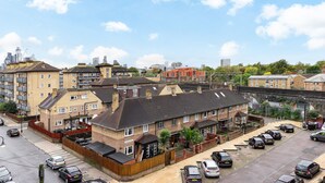 A residential area with multiple two-story houses, a parking lot, and a railway track overhead. - City Gate Guest House (London)